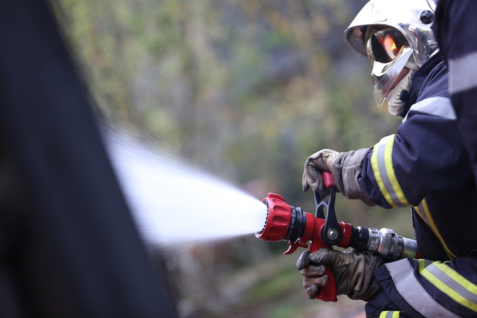 Un pompier avec sa lance à incendie activée