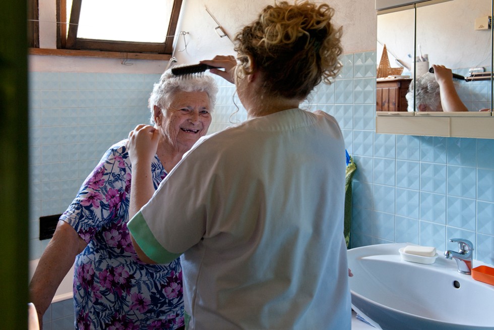 Une personnelle soignante recoiffe une personne âgée