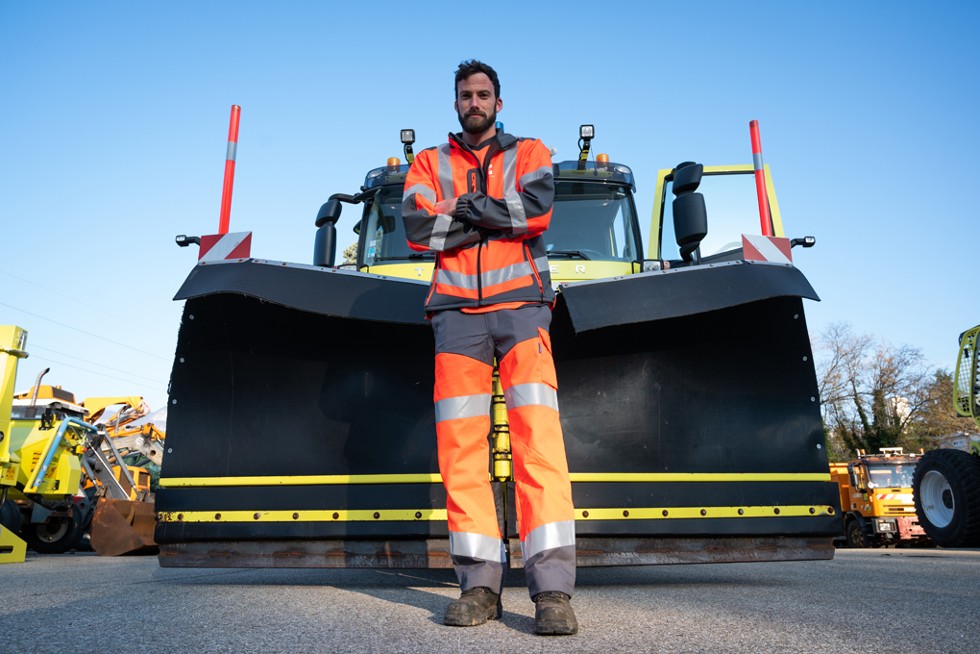 Un agent pose devant un camion de déneigement