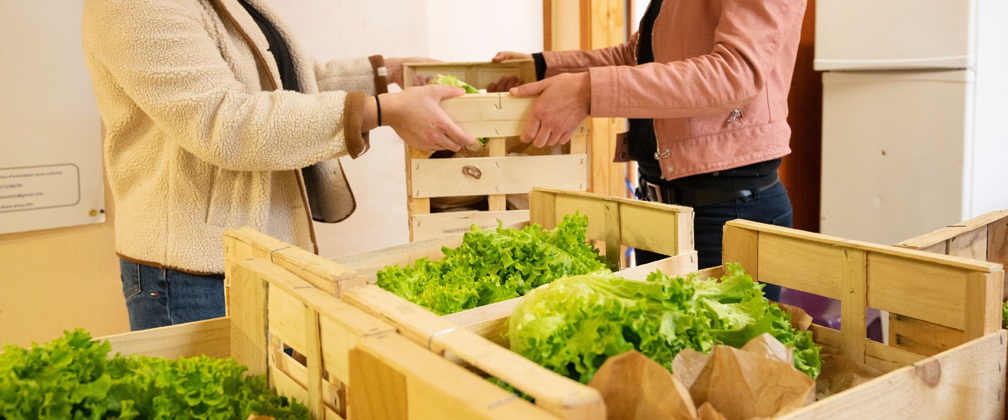 Deux personnes se passant une cagette avec des légumes