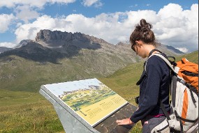 Une randonneuse devant un panneau indicateur